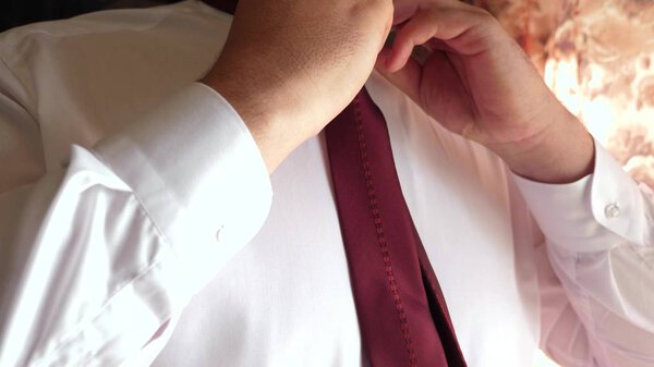 По утрам бизнесмен надевает галстук на работу. крупным планом. человек связывает красный галстук. офисный работник одевается утром
.