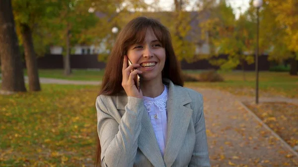 Telefone celular andando pelo parque de outono e sorrindo — Fotografia de Stock