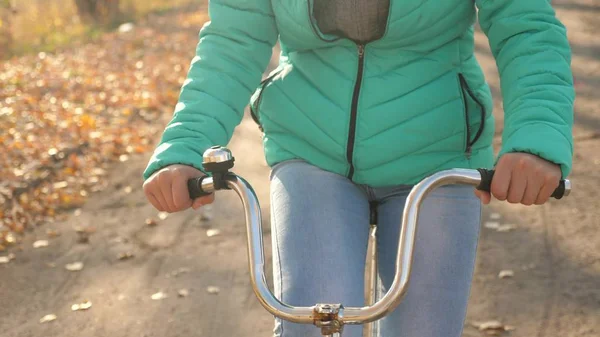 Menina segura volante curvo e monta uma bicicleta no parque de outono, close-up — Fotografia de Stock