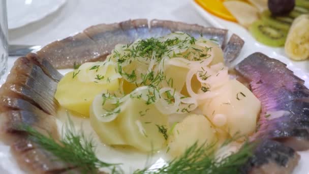 Arenque fatiado em uma placa com batatas cozidas polvilhadas com endro de cebola. mesa de servidor em um restaurante. comida deliciosa na mesa. tudo incluído — Vídeo de Stock