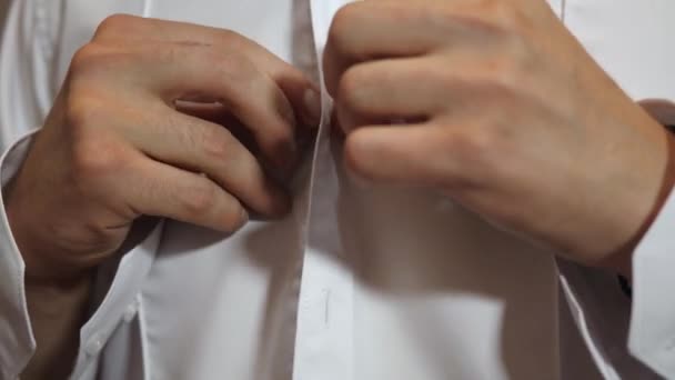 O homem de manhã veste uma camisa para o trabalho. Close-up. O empresário veste uma camisa branca de manhã, abotoando os botões com as mãos. Trabalhador das empresas de conceito . — Vídeo de Stock