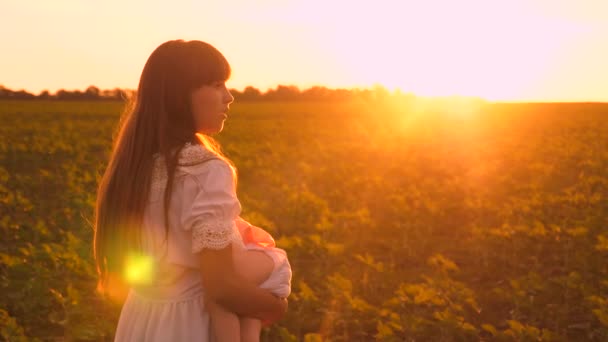 Concept d'enfance heureuse. petite fille s'endort dans les bras de sa mère dans de beaux rayons de soleil. famille heureuse marchant au coucher du soleil dans le parc. concept de famille heureuse. Travail d'équipe . — Video