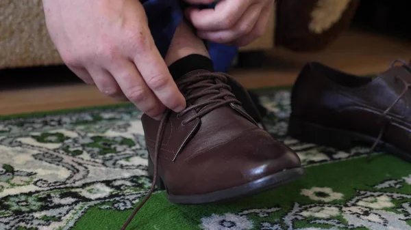 Man tying shoelaces on brown shoes, a man in a white shirt and dark trousers. Businessman gets dressed in the morning to work. — Stock Photo, Image