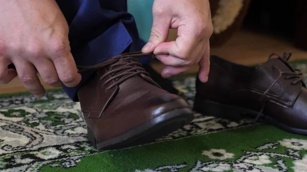 Man tying shoelaces on brown shoes, a man in a white shirt and dark trousers. Businessman gets dressed in the morning to work. — Stock Photo, Image