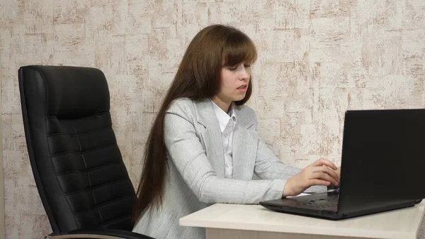 Joven mujer de negocios en su lugar de trabajo. hermosa mujer de negocios en correspondencia de negocios en un ordenador portátil. muchacha joven que trabaja en la oficina en el ordenador . — Foto de Stock