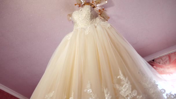 Vestido de novia blanco colgando en la habitación de la novia en la lámpara de araña. hermoso vestido de bola blanca colgando del techo. concepto de moda — Vídeos de Stock