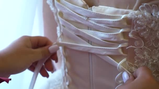 Vestido de noiva close-up. Dama de honra curvando um vestido de noiva com um arco. A noiva está a preparar-se para a cerimónia de casamento. Vestido de baile para a menina . — Vídeo de Stock