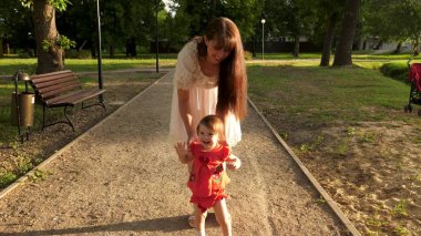 Çocuk yaz aylarında yol park boyunca yürümeyi öğrenir, Anne ile bebek yürüyor