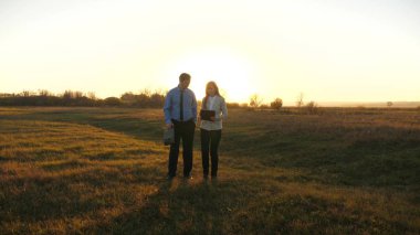 İş adamı tablet ile evrak çantası ve iş kadınla günbatımı ve gülmek de birlikte çalışmaya katılıyorum. İş ortağı ile iş toplantısı