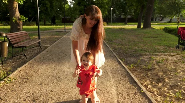 Criança aprende a andar ao longo do caminho no parque no verão, mãe caminha com o bebê — Fotografia de Stock