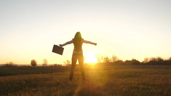 Gratis affärskvinna med portfölj i handen och i kostym är framgång vid solnedgången i ljusa strålar från solen — Stockfoto