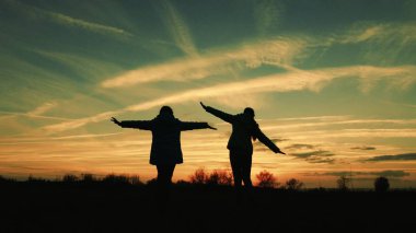 Gün batımında akşamları çocuk oyun. kızlar süper kahramanlar karşı güzel gökyüzü zemin çayır rastlamak. uçan çocuk rüyası. mutlu çocukluk kavramı. ekip çalışması kız