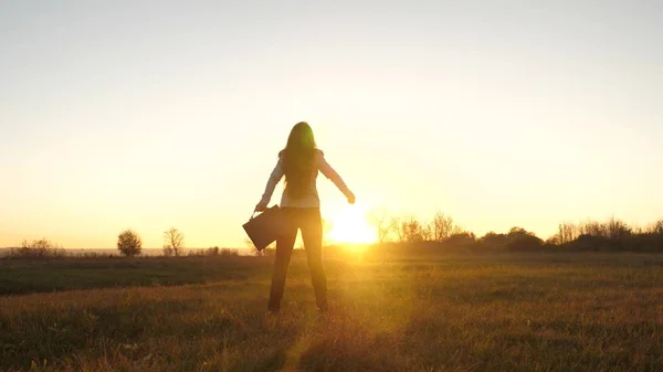 Femme d'affaires libre avec mallette à la main et en costume d'affaires est le succès au coucher du soleil dans les rayons lumineux du soleil — Photo