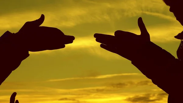 Дети делают форму собаки с руками на закате. Девушки держат жест собачьего символа пальцами к небу. Дети показывают руками силуэт животного. теневая игра — стоковое фото