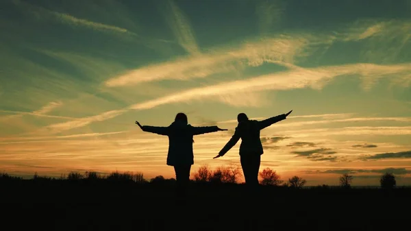 Los niños juegan por la noche al atardecer. niñas superhéroes corren a través de la pradera contra el telón de fondo del hermoso cielo. los niños sueñan con volar. concepto de la infancia feliz. trabajo en equipo novia —  Fotos de Stock