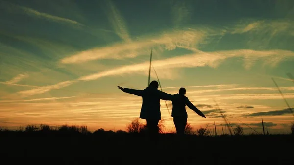 Los niños juegan por la noche al atardecer. niñas superhéroes corren a través de la pradera contra el telón de fondo del hermoso cielo. los niños sueñan con volar. concepto de la infancia feliz. trabajo en equipo novia — Foto de Stock