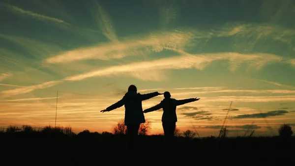 I bambini giocano la sera al tramonto. supereroi ragazze corrono attraverso il prato sullo sfondo del bel cielo. i bambini sognano di volare. concetto di infanzia felice. lavoro di squadra fidanzata — Foto Stock