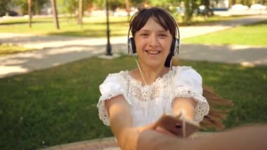 kız ve erkek dans el ele. Ağır çekim. kulaklık kız gülümseyerek ve dans ve onun sevgili adamla iplik telefon ile parkta elele. sevgi dolu bir çift takım çalışması