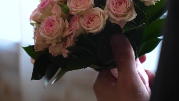 Beau bouquet de fleurs dans les mains d'un homme à la mode pour la femme qu'il aime. Gros plan. bouquet de roses multicolores entre les mains d'un homme . — Video