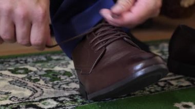 adam kahverengi ayakkabı, beyaz bir gömlek ve pantolon koyu bir adam üzerinde ayakkabı bağcığı bağlama. İşadamı çalışmak için sabah giyinmiş.