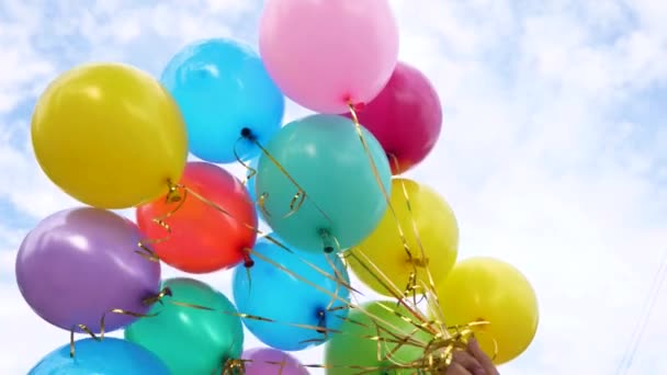 Beautiful multicolored balloons in the blue sky holds the hand. The concept of a wonderful holiday. color decorations at a party. — Stock Video