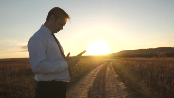 Businessmans doigts écran tactile de la tablette, smartphone. mains masculines tiennent une tablette et vérifier les e-mails dans le parc au coucher du soleil. main masculine tape un message mobile sur l'écran du smartphone . — Video