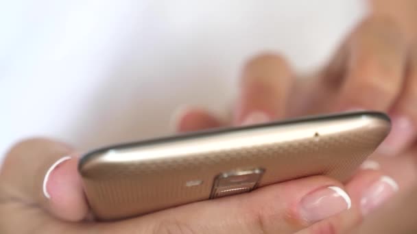 A girls hand is typing a mobile message on the smartphone screen. Womens hands hold the smartphone and browser the website and email. close-up. — Stock Video