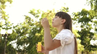 İlkbahar, yaz ve gülümseyen içinde parkta sabun köpüğü üfleme güzel kız. Ağır çekim. parkta oynayan genç kız.