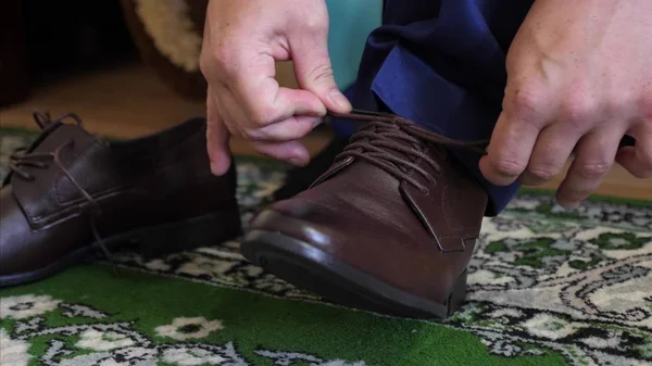 Man tying shoelaces on brown shoes, a man in a white shirt and dark trousers. Businessman gets dressed in the morning to work. — Stock Photo, Image