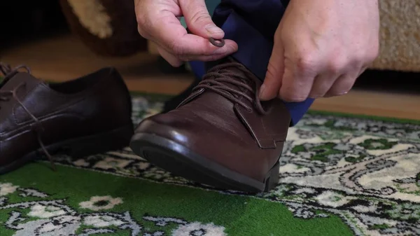 Man tying shoelaces on brown shoes, a man in a white shirt and dark trousers. Businessman gets dressed in the morning to work. — Stock Photo, Image