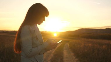 Eller bir tablet tutarak ve e-postaları parkta günbatımında kontrol. kızın parmak dokunmatik ekran tablet, smartphone... Kızlar el bir mobil ileti smartphone ekranında yazdırır..