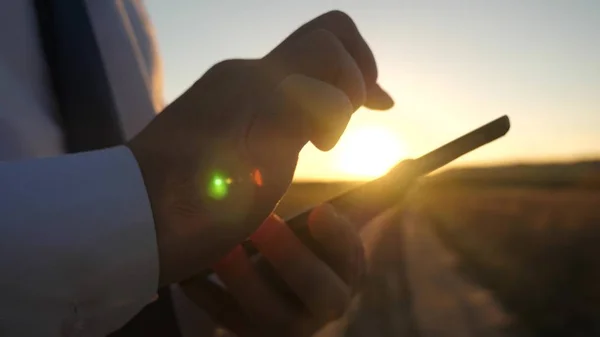 Empresário a trabalhar num tablet ao pôr-do-sol. as mãos de um homem estão dirigindo seus dedos sobre o tablet. close-up. homem verifica e-mail . — Fotografia de Stock