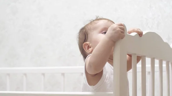 Bebê bonito joga em um berço — Fotografia de Stock