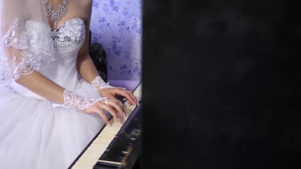 La mariée interprète un morceau de musique au piano. mains d'une jeune fille jouant de l'instrument clavier clave. fille en robe blanche jouant pour le piano noir. affaires de musique . — Video