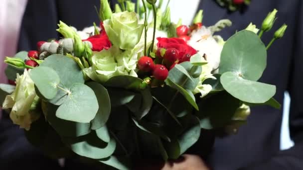 Krásnou kytici rudých růží v rukou muži v saku v bílé košili a červenou kravatu. krásnou kytici květin v rukou módní muže, pro ženu, kterou miluje. detail. — Stock video