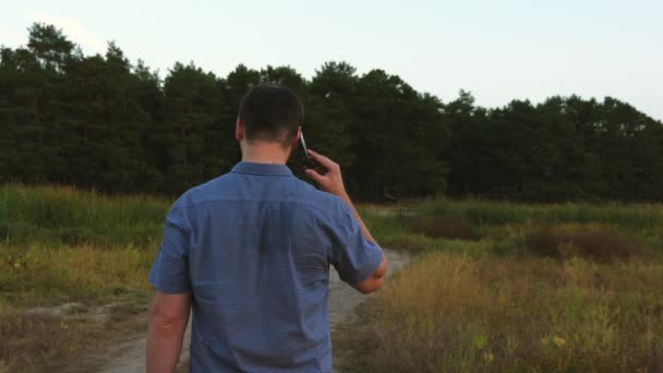 Człowiek na leśnej drodze i rozmowy na smartfonie. turystycznych w lesie. człowiek jest rozmowa na telefon podczas spaceru w parku wieczorem. — Wideo stockowe
