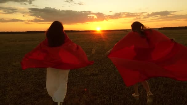 Meninas jogar super-heróis correndo através do campo com trigo contra o céu azul — Vídeo de Stock