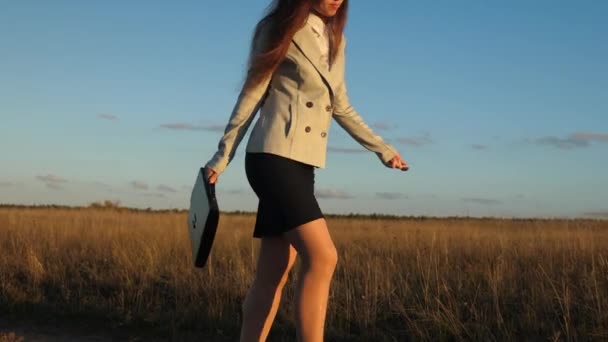 Mujer de negocios caminando por un camino rural con un maletín en la mano. sexy mujer de negocios chica que trabaja en el área rural. agricultora inspecciona la tierra al atardecer. concepto de empresa agrícola . — Vídeos de Stock