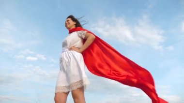 Kız bir süper kahraman olma hayalleri. seksi süper kahraman kız kırmızı bir Görünmezlik pelerini rüzgarda çırpınan alanında ayakta. bir kırmızı pelerin rüya ifadesinde genç kız