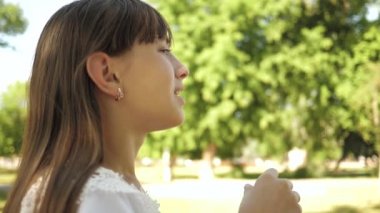 Genç Kız parkta oynarken ve kabarcıklar yakın çekim üfleme. Ağır çekim. İlkbahar, yaz ve gülümseyen içinde parkta sabun köpüğü üfleme güzel kız.