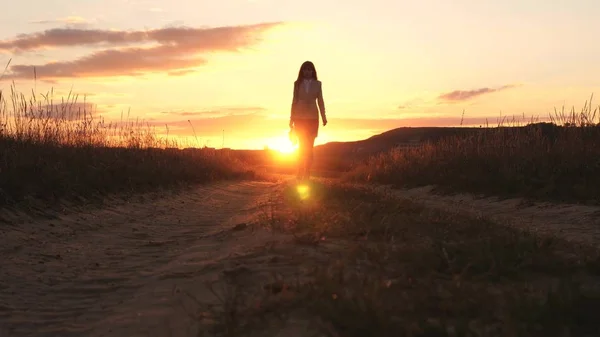 Sexy Business woman walking along a country road with a briefcase in hand, the sun shimmers at sunset. Sexy business girl working in the countryside. beautiful girl travels the countryside. — Stock Photo, Image