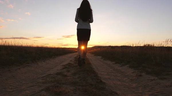Une femme d'affaires marche le long d'une route de campagne avec une tablette à la main, le soleil miertsaet entre les jambes des femmes. fille d'affaires sexy courir dans la campagne. fille sexy voyage dans la campagne — Photo