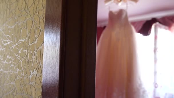 Wunderschönes weißes Ballkleid, das von der Decke hängt. Modekonzept. Weißes Hochzeitskleid hängt im Zimmer zur Braut am Kronleuchter. — Stockvideo