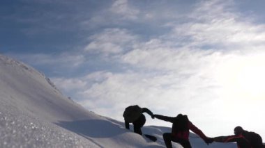 alpinist birbirlerine bir karlı dağın tepesine tırmanmak bir arkadaşa yardım etmek için ellerini hareket. ekip çalışması kazanmak arzusu. Yolcuları kışın karlı dağa tırmanmak. Spor turizmi kavramı.