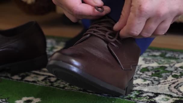 Uomo allacciatura lacci delle scarpe su scarpe marroni, un uomo in camicia bianca e pantaloni scuri. primo piano. L'uomo d'affari si veste la mattina per andare al lavoro. uomo che indossa scarpe alla moda — Video Stock