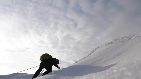 Tres alpenistas en invierno trepan la cuerda en la montaña. Los viajeros suben la cuerda a su victoria a través de la nieve cuesta arriba en un fuerte viento. turistas en invierno trabajan juntos como equipo superando las dificultades . —  Fotos de Stock