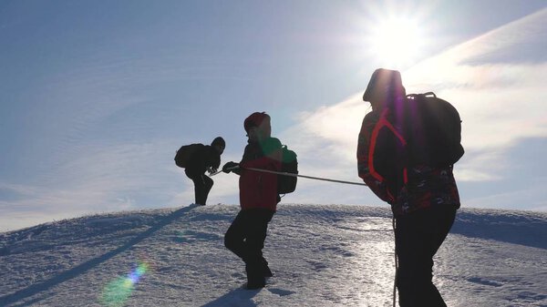 team of business people climb to the top of their success. teamwork business people. three climber climb rope on snowy mountain. people work together to overcome difficulties.