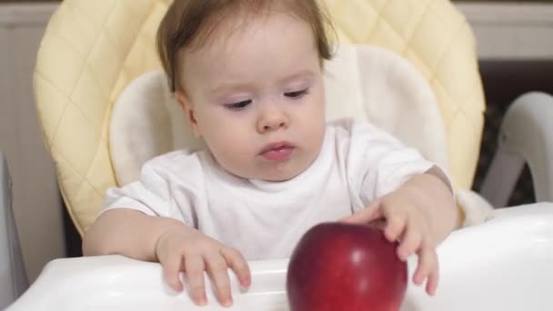 Little child plays with red apple on table — Stock Video