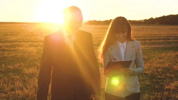 teamwork of business people.businessman and businesswoman discuss teamwork plan in the park at sunset. team of business people go to victory and success. teamwork and victory. yellow sunset