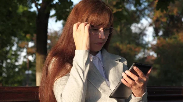 womanbusinessman checks email on tablet in summer park on a bench.